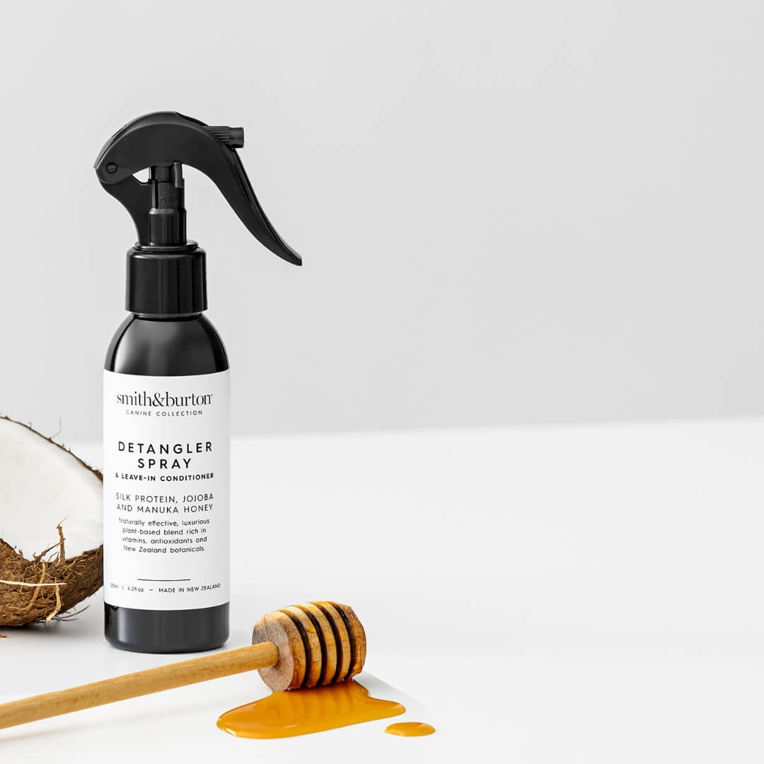 Detangler spray bottle with honeycomb and honey on a white background